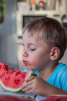 Cute boy eating watermelon at home. Real emotions without posing. children