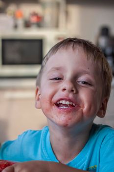 Cute boy eating watermelon at home. Real emotions without posing. children