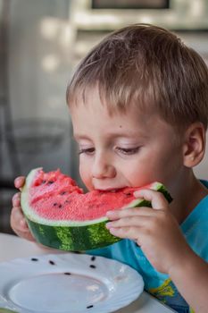 Cute boy eating watermelon at home. Real emotions without posing. children