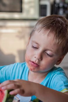 Cute boy eating watermelon at home. Real emotions without posing. children