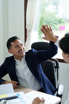 Portrait of two young Asian entrepreneurs congratulating them with smiling faces after successful investment negotiations.