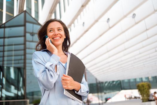 Excited caucasian businesswoman standing near office building have phone conversation feeling surprised Happy female worker happy smile after hear good news. positive cell phone conversation
