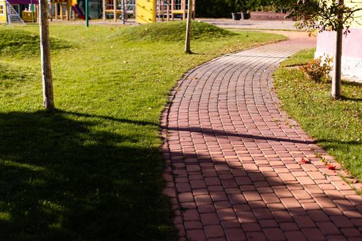 Cobblestone road in the park in autumn and green trees in background.