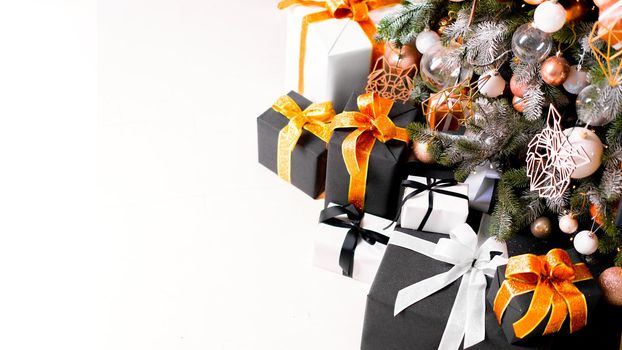 Christmas present gift box stacked close up. Holiday sale concept. Many gift box black, white, orange color with gold ribbon and light garland