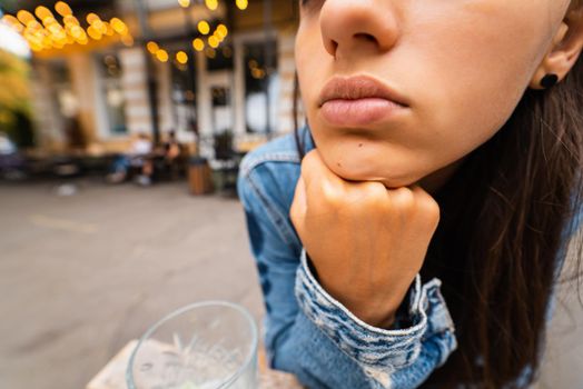 Close view of woman sitting, leaning on her fist outdoor