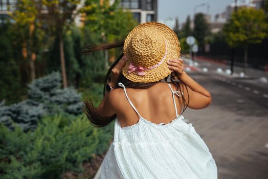 Young beautiful brunette woman in dress walking on the street, summer embankment outdoors