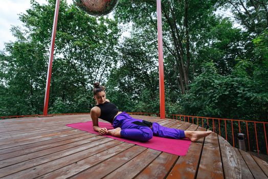 A young woman in doing yoga in the yard on the veranda