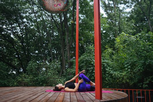 A young woman in doing yoga in the yard on the veranda
