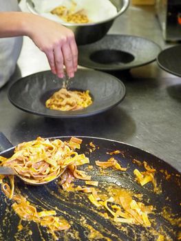 closeup of a chef hand wearing gloves serving and decorating a plate of pasta