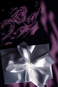 Happy holidays, luxe shopping and love gifts concept - Luxury holiday silk gift box and bouquet of roses on purple background, romantic surprise and flowers as birthday or Valentines Day present