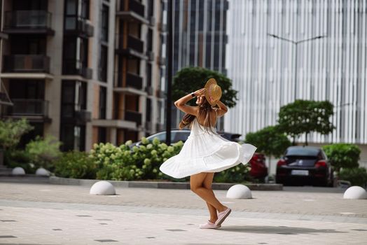 Young sexy beautiful pretty woman in white dress walking at city street