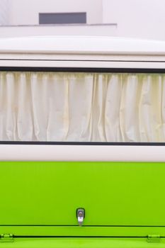 Curtained window of a bright white and green retro Volkswagen van close up