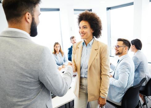 Portrait of a young businesswoman shaking hands with a coworker during a meeting in the office. Teamwork and success concept