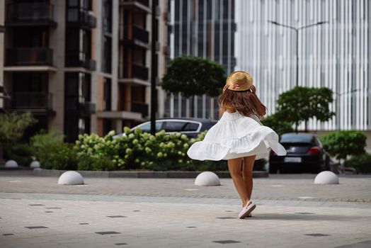 Young sexy beautiful pretty woman in white dress walking at city street