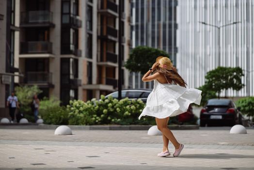 Young sexy beautiful pretty woman in white dress walking at city street