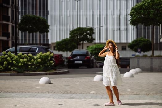 Young sexy beautiful pretty woman in white dress walking at city street