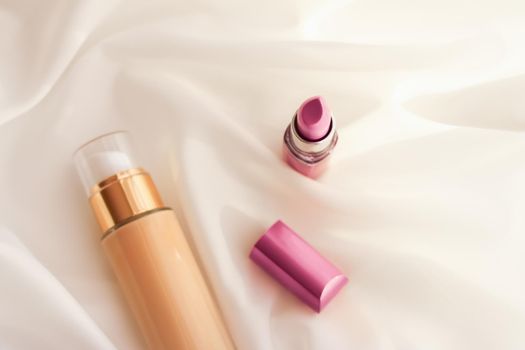 Cosmetic branding, glamour and skincare concept - Beige tonal cream bottle make-up fluid foundation base and pink lipstick on silk background, cosmetics products as luxury beauty brand holiday design