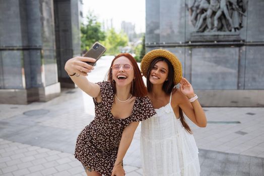 Two joyful cheerful girls taking a selfie outdoors