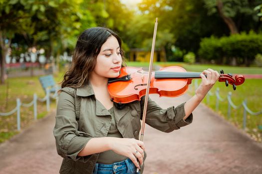 Woman playing the violin in the street. Close up of violinist girl playing in a park. Artist woman playing the violin outdoors, woman playing the violin in a nice park. Violinist woman concept