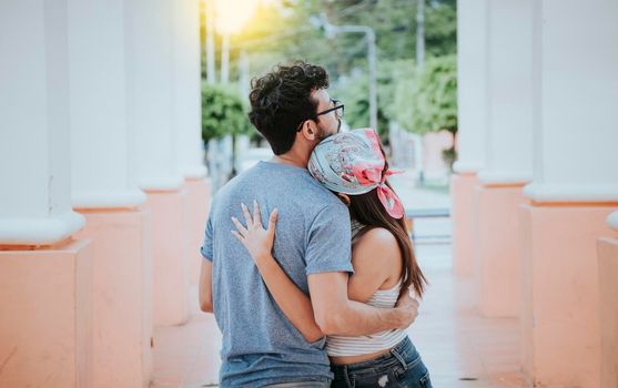 Back view of young woman hugging her boyfriend. Back view of girl hugging her boyfriend outdoors, Back view of happy couple hugging outdoors