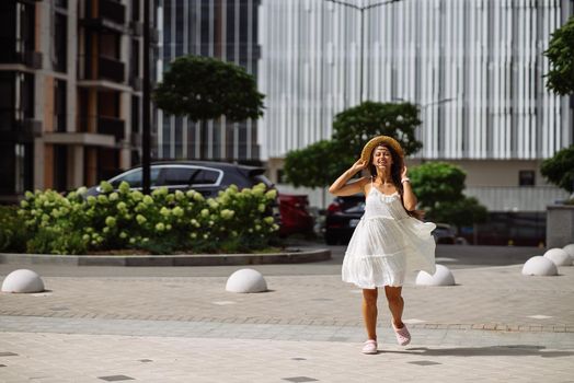 Young sexy beautiful pretty woman in white dress walking at city street