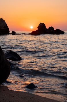 Beautiful view of orange sunset seascape with rocks in Italy. Tropical colorful sunrise landscape