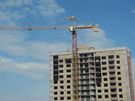 Crane and building under construction against blue sky.