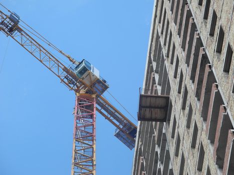 Crane and building under construction against blue sky.