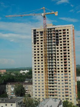 Crane and building under construction against blue sky.