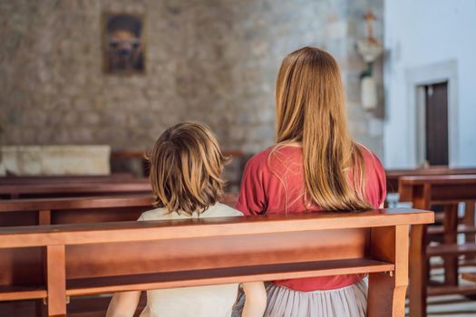 A Christian mom tells her son Bible stories about Jesus sitting in church. Faith, religious education, modern church, mother's day, maternal responsibilities, mother's influence on son's worldview formation.