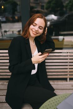 Attractive brunette woman at the street cafe reading a text messageon a phone.