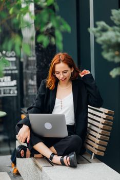 Photo portrait of gorgeous attractive woman working on laptop typing sitting in cafe drinking coffee