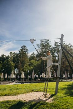 A young woman wants to go bungee from the tower in the rope park