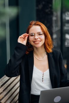Beautiful redhead woman working on laptop at outdoors cafe