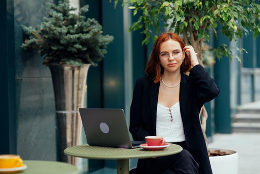 Happy young woman in a street cafe looks into the camera