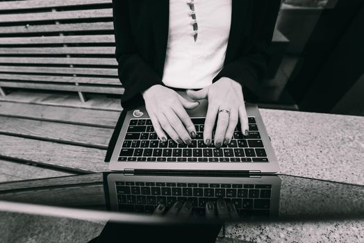 Close up image of woman hands typing and writing on laptop, working on cafe.