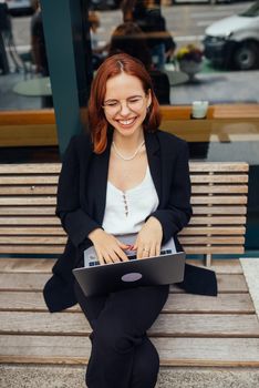 Photo portrait of gorgeous attractive woman working on laptop typing sitting in cafe drinking coffee