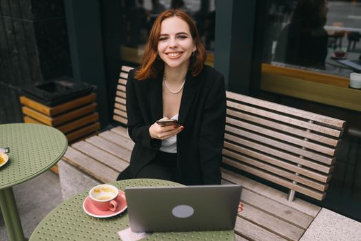 Attractive brunette woman at the street cafe reading a text messageon a phone.