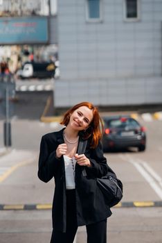 Young beautiful smiling happy woman with backpack poses on a camera while standing on the road