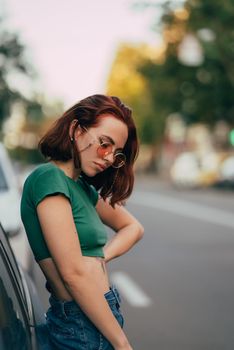 Young woman in glasses posing near car