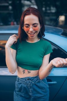 Young woman in glasses posing near car