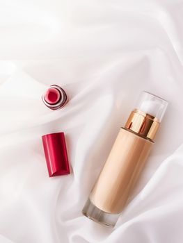 Cosmetic branding, glamour and skincare concept - Beige tonal cream bottle make-up fluid foundation base and red lipstick on silk background, cosmetics products as luxury beauty brand holiday design