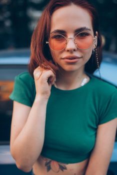 Young woman in glasses posing near car