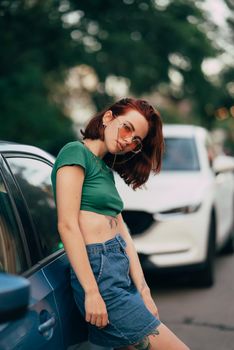 Young woman in glasses posing near car