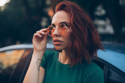 Young woman in glasses posing near car