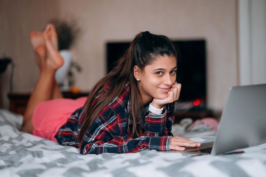 Selective focus of young woman work while with laptop lying on bed