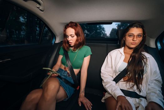 Real life of friends together in the back seat of a taxi holding cellphones and checking messages.