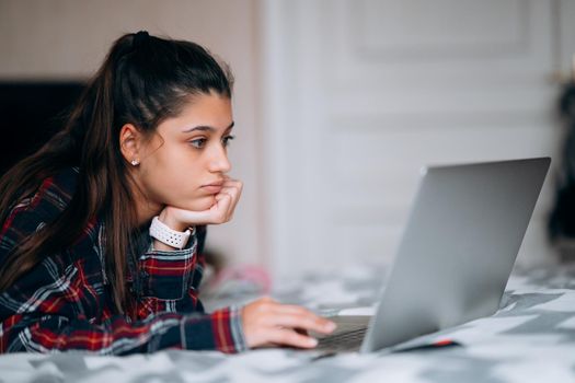 Selective focus of young woman work while with laptop lying on bed