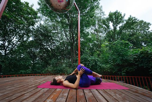 A young woman in doing yoga in the yard on the veranda