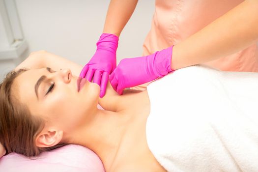 Waxing. Depilation under the armpits of the young woman lying with closed eyes in the spa salon